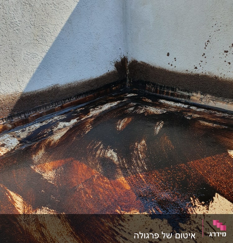 חומר איטום כהה מרוח על רצפה בפינה